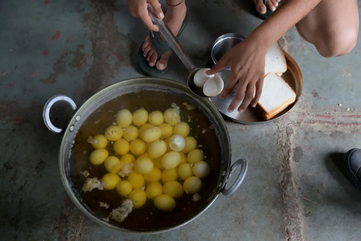 A 13 éves Anjali, a 15 éves Naitik Rana és a 16 éves Swati Berwal főtt tojásból készítenek reggelit maguknak – Fotó: Anushree Fadnavis / Reuters