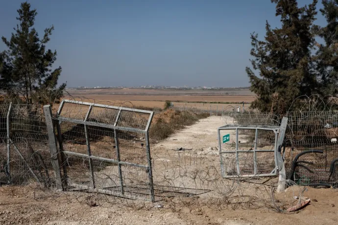 A Kfar Aza kibuc beszakított kapuja, háttérben a Gázai övezet, ahonnan a terroristák érkeztekoktóber 7-én, hogy lemészárolják a település lakóit. A kiégett autók mellett egy robogó, amivel az egyik Hamász-fegyveres érkezett – Fotó: Huszti István / Telex