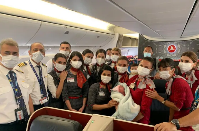 A kabinszemélyzet a Turkish Airlines Dubaj-Birmingham evakuációs járatán született afgán csecsemővel 2021. augusztus 28-án – Fotó: Turkish Airlines / Anadolu Agency / Getty Images