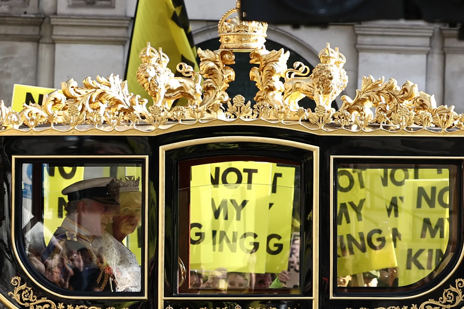 III. Károly brit király és Kamilla királyné a gyémántjubileumi állami hintón halad el a „Nem az én királyom” feliratú plakátokat tartó tüntetők mellett Londonban 2023. november 7-én – Fotó: Henry Nicholls / AFP