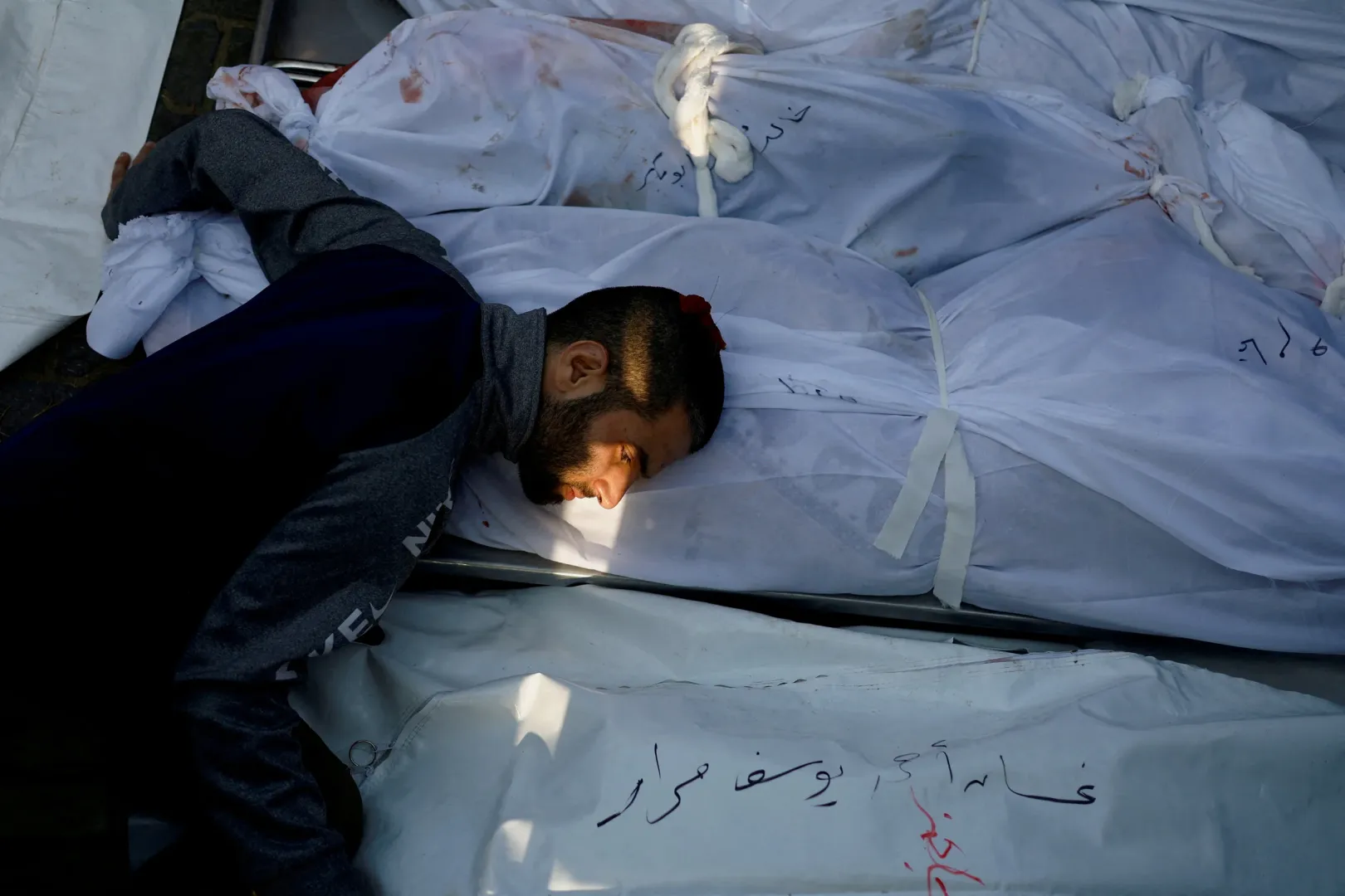 Gyászoló férfi borul a halottakra az izraeli csapásokban megölt palesztinok temetésén Hán Júniszban – Fotó: Mohammed Salem / Reuters