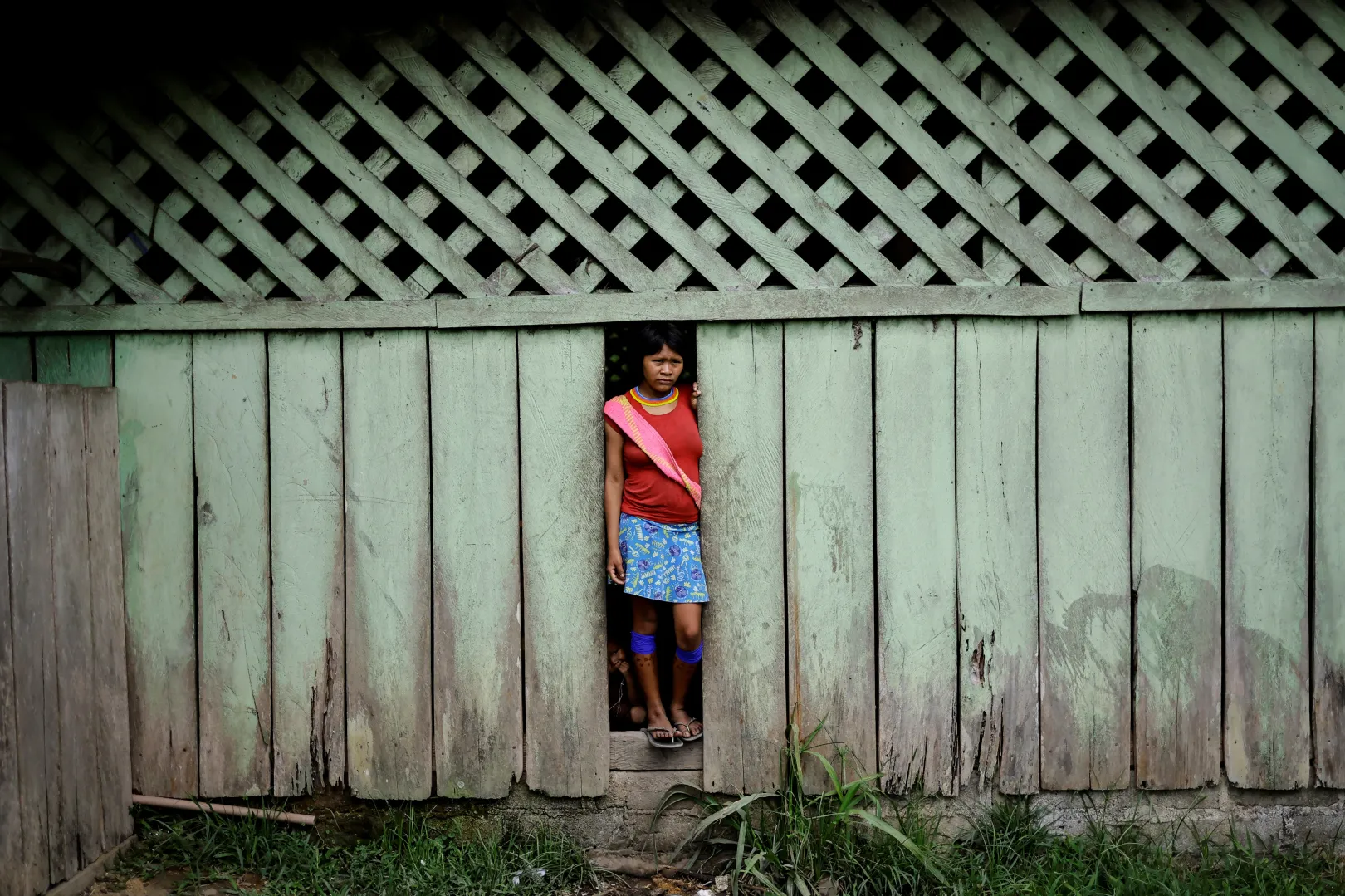 Őslakos nő néz ki a beteg janomamik számára létrehozott egészségügyi menedék ajtajából – Fotó: Ueslei Marcelino / Reuters