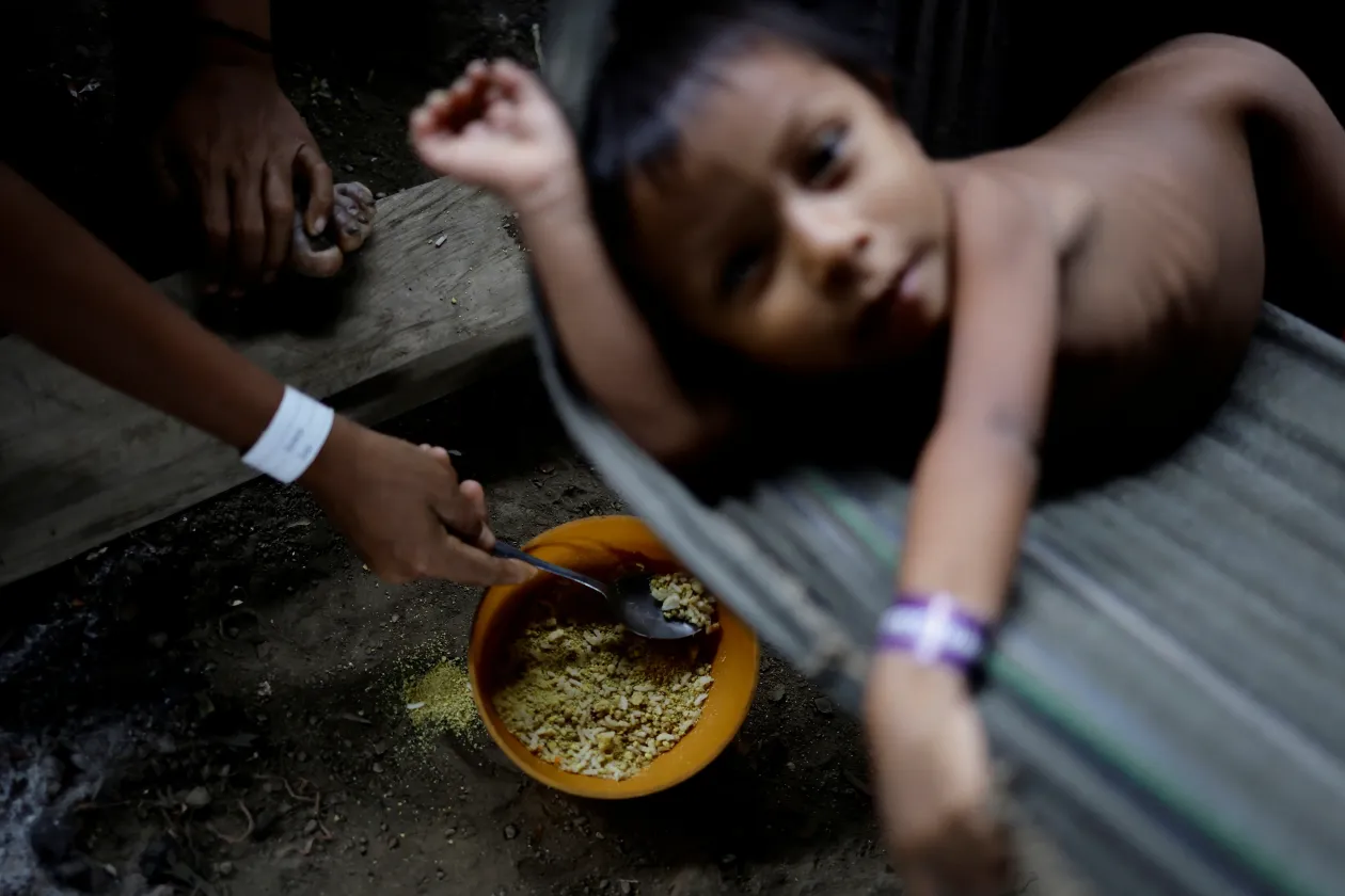 Balra: egy janomami gyermeket rizs és farofa keverékével etet az édesanyja, miközben egészségügyi ellátásban részesül a betegszállón. Jobbra: ételosztásra vár egy janomami család az egészségügyi központban – Fotó: Ueslei Marcelino / Reuters