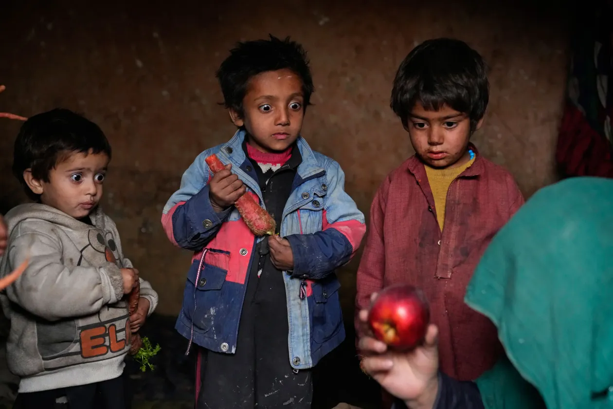 Balra három kisgyermek bámulja kigúvadt szemekkel az egy szem almát, amit édesanyjuk koldult össze a belső menekültek Kabul határában felállított menekülttáborában 2023. február 2-án. Jobbra egy Pakisztánból frissiben deportált afgán nő pihen egy kanapén a sivatagban, az afgán-pakisztáni határ közelében a visszatoloncoltak tábora mellett 2023. november 17-én.