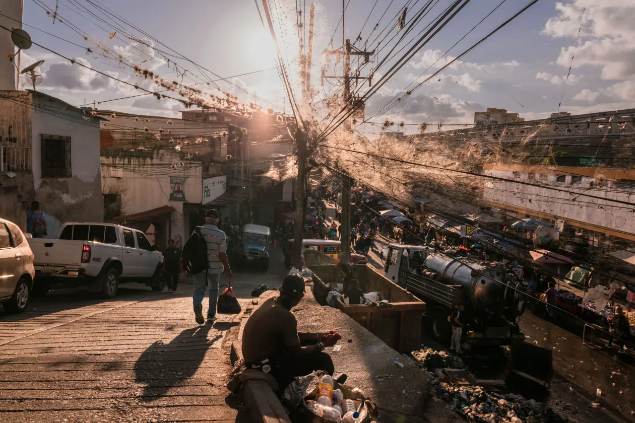 Férfiak élelem után kutatnak egy hulladékgyűjtő konténerben egy forgalmas utcai piacon. Az OHCHR szerint a lakosság felének a jövedelme nem elegendő az alapvető élelmiszer-szükségletek kielégítéséhez. Caracas, Venezuela, 2023. január 10. // Két halász evez a Maracaibo-tó zöld vizén, amelyet az olaj mellett a műtrágya, szennyvíz és más vegyi anyagok által okozott algák is elleptek. Cabimas, 2022. november 24.