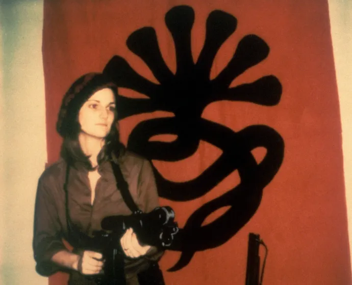 Patty Hearst gépfegyverrel a Szimbionista Felszabadítási Hadsereg zászlója előtt 1974-ben – Fotó: Bettmann / Getty Images