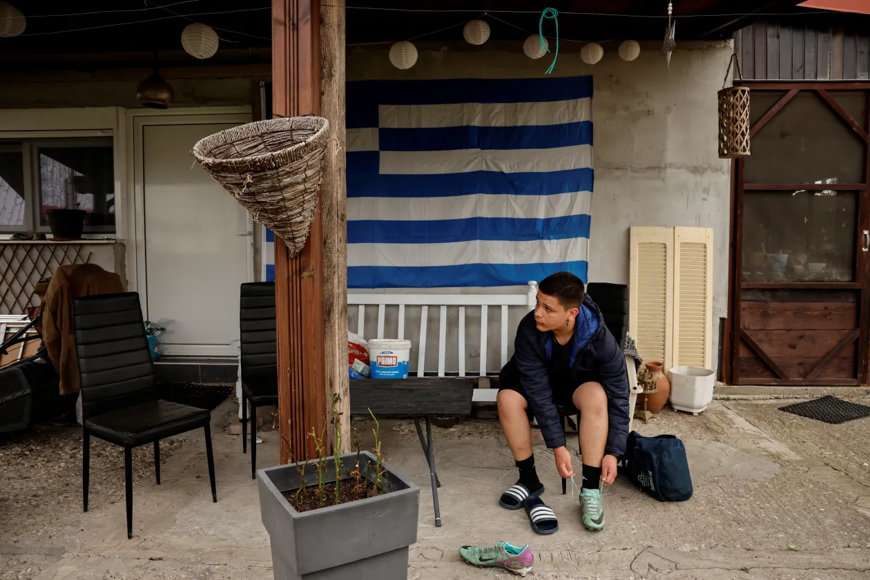 Balra: A helyiek focimeccset néznek Orménióban. Jobbra: A 13 éves Nikólaosz stoplis cipőt húz a fociedzése előtt – Fotó: Louisa Gouliamaki / Reuters
