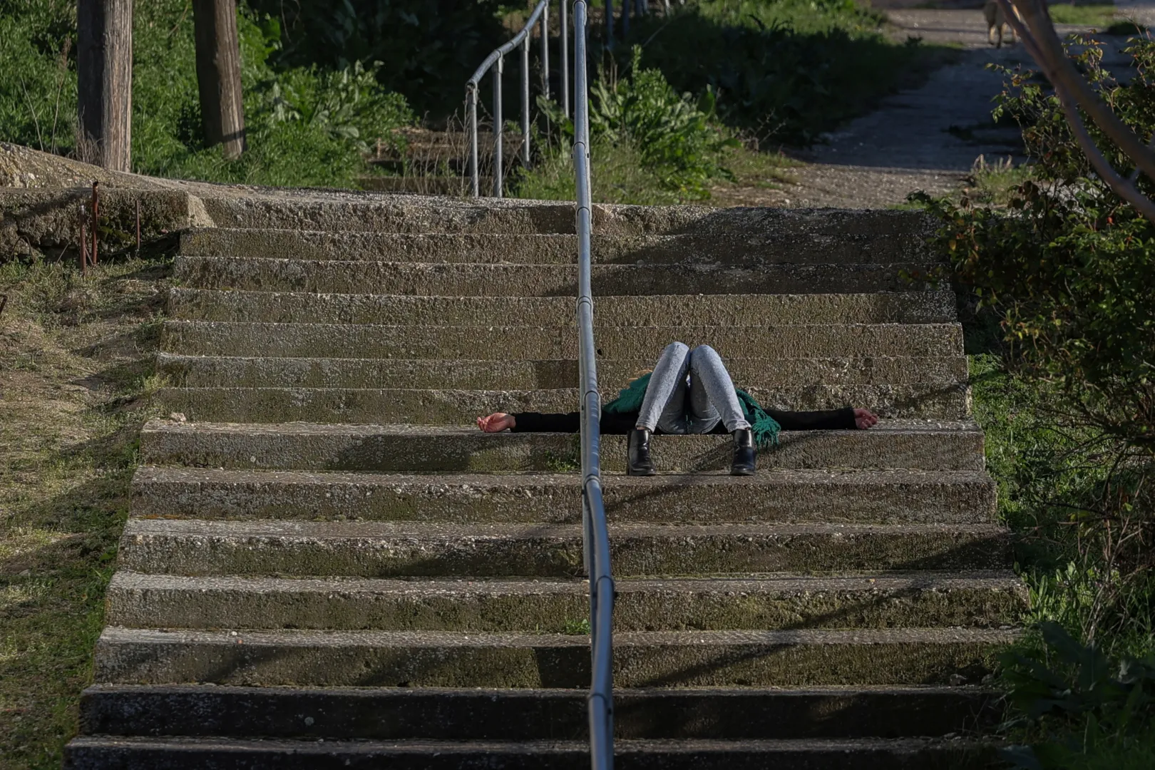 Fiatal lány fekszik a falu lépcsőin – Fotó: Louisa Gouliamaki / Reuters