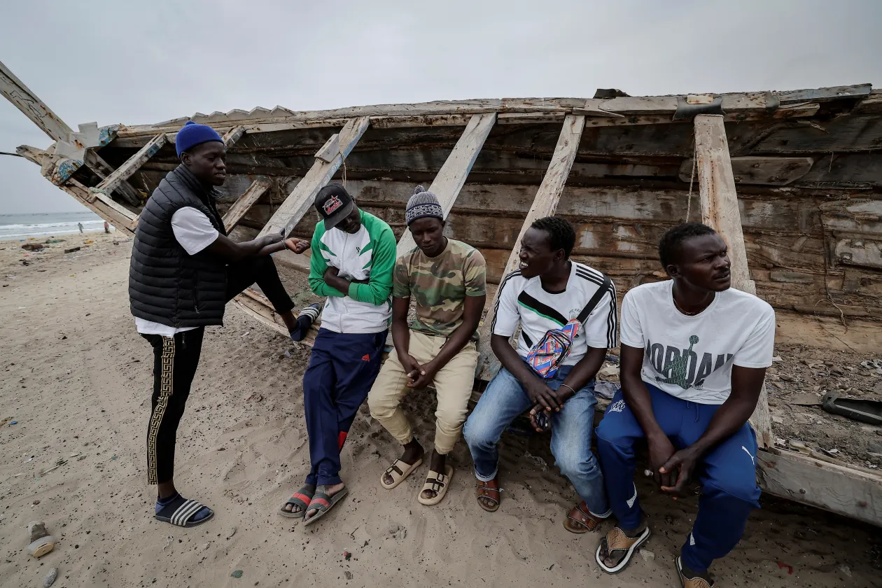 Pirogue-nak nevezett halászhajók az atlanti partokon (balra); Mbaye és barátai – köztük hajószerencsétlenségek túlélői – ülnek egy pirogue-on – Fotó: Zohra Bensemra / Reuters