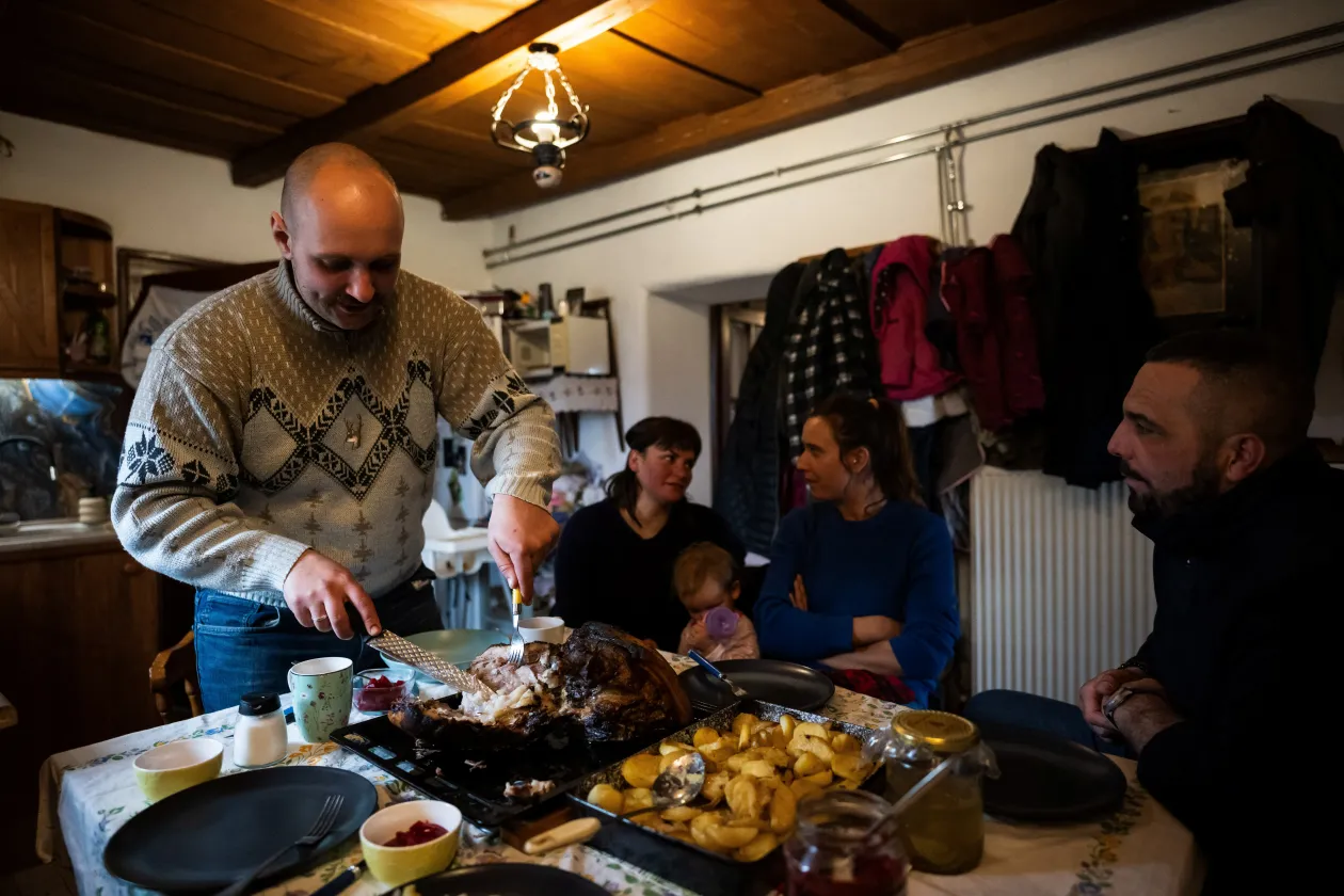 Cintia Mnyere lulling her baby daughter to sleep on the porch of their farmhouse in March 2024. In the other picture, László and his wife Cintia, their daughter Boróka and their friends Krisztián Kisjuhász and his wife Zsanett Homoki are having lunch in March 2024 Photo: Márton Mónus / Reuters