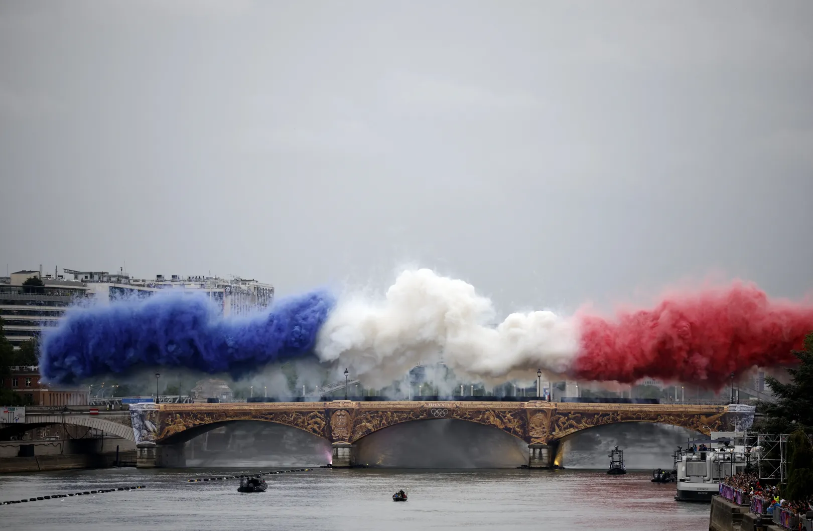 Már a megnyitó első pillanatai ikonikusra sikerültek: a francia trikolór füstfelhője borította az Austerlitz hidat a Szajna fölött – Fotó: Albert Gea / Reuters