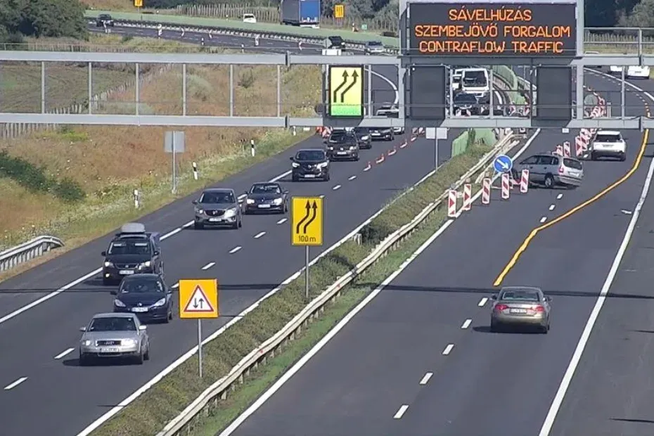 Megpróbál lehúzódni jobbra, elüt egy bóját a szürke Opel, majd balra rántva a kormányt tiszta erővel áttöri az M1-es szalagkorlátját