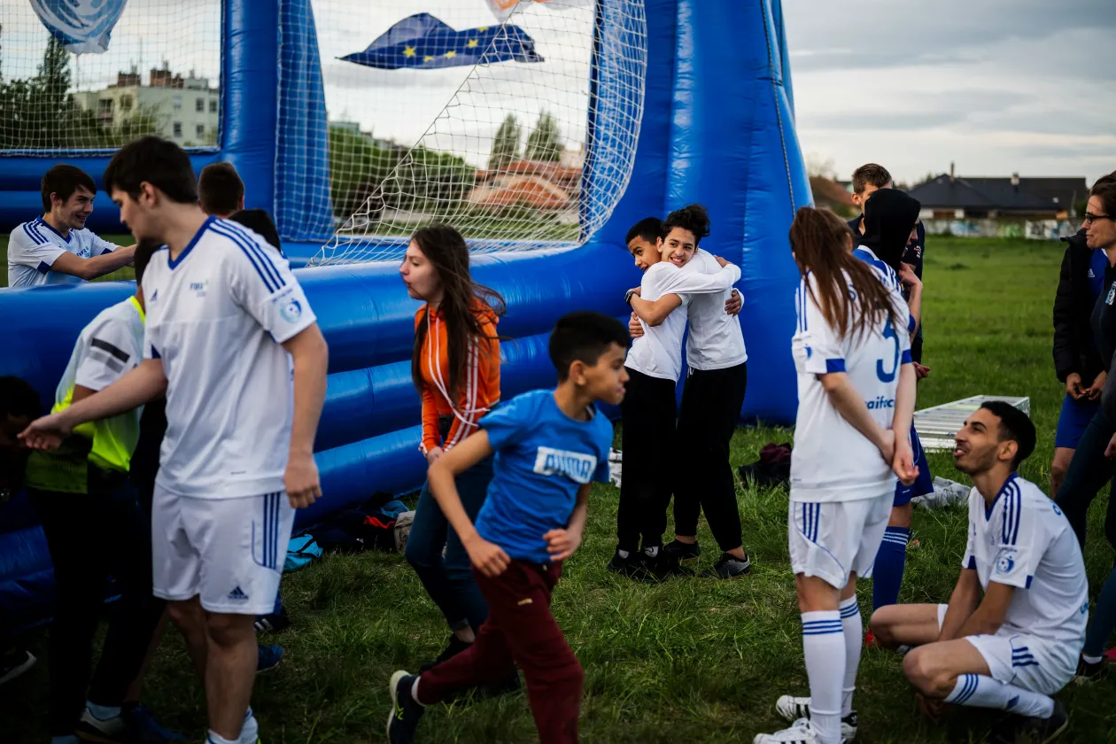 Az Oltalom Sportegyesület labdarúgócsapatának két tagja ölelkezik egy edzés után Budapesten, 2021. május 2-án // A három testvér, a 17 éves Hamza Dávid, a 21 éves Hamza József és a 22 éves Hamza György zászlókba burkolózva próbálják melegíteni magukat az edzésen Budapesten, 2021. május 2-án – Fotó: Mónus Márton / Reuters