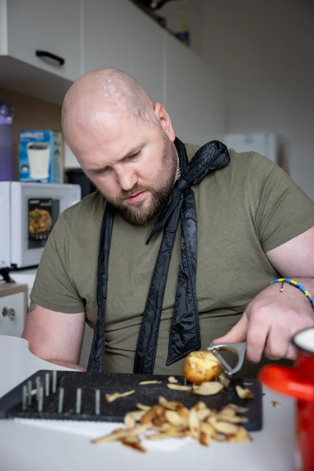 A soldier with a head injury learns to peel potatoes in the hospital's communal kitchen, a movement sequence that develops motor skills. Patients prepare borscht soup together during a therapy session