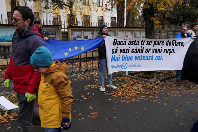 Orosz veszélyre figyelmeztető bannert és EU-zászlót nyújtanak ki a nemzeti ünnepi felvonulásról hazatérők előtt – Fotó: Andreea Campeanu / Reuters