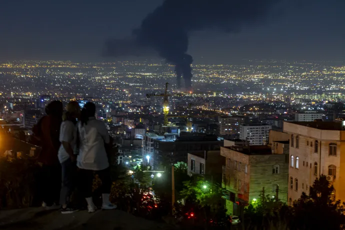Helyiek egy dombtetőről nézik, ahogy füst száll Teherán felett egy izraeli légitámadás után 2025. június 14-én éjszaka – Fotó: Khoshiran / Middle East Images / AFP