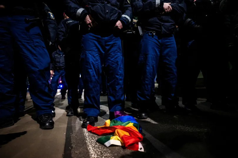 Szivárványos zászló hever a rendőrök előtt egy tüntetésen március 25-én, miután a magyar parlament elfogadta a Pride megtiltását célzó törvényt, korlátozva a gyülekezési jogot // Egy nő meggyújtja az Orbán Viktor magyar miniszterelnököt ábrázoló plakát cigarettáját – Fotó: Mónus Márton / Reuters