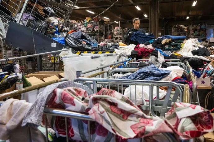 Egy dolgozó szortírozza a beérkező ruházati cikkeket egy stockholmi válogatóközpontban – Fotó: Jonathan Nackstrand / AFP