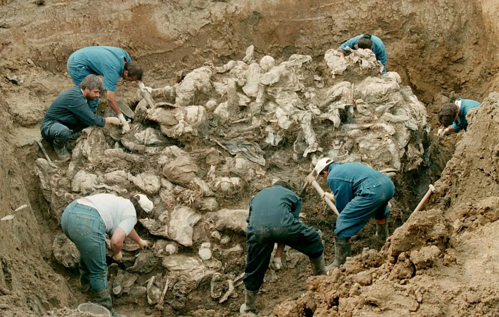 A hágai Nemzetközi Háborús Büntetőbíróság igazságügyi szakértői egy halom részben bomlott holttestet vizsgálnak 1996. július 24-én, amelyet egy tömegsírban találtak Pilica faluban, Szarajevótól mintegy 300 km-re északkeletre. Az áldozatok állítólag a Srebrenicából eltűntek közül valók – Fotó: Odd Andersen / AFP