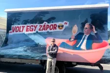 Magyar Péter egy őt lejárató plakát előtt pózolt