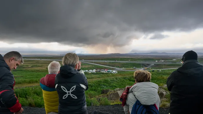 Turisták figyelik az izlandi Grindavik közelében lévő vulkán kitörést a szomszéd településen, Keflavikban 2025. július 16-án – Fotó: Halldor Kolbeins / AFP