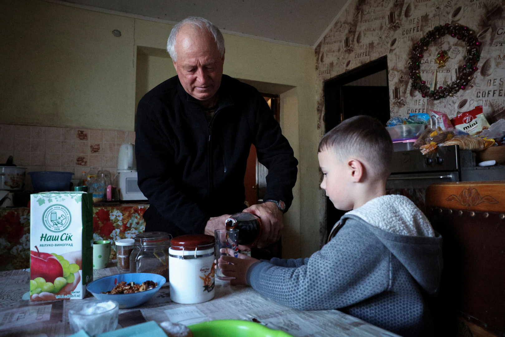 A 66 éves Volidimir Tkacsenko üdítőt tölt unokájának, Makszimnak – Fotó: Violeta Santos Moura / Reuters