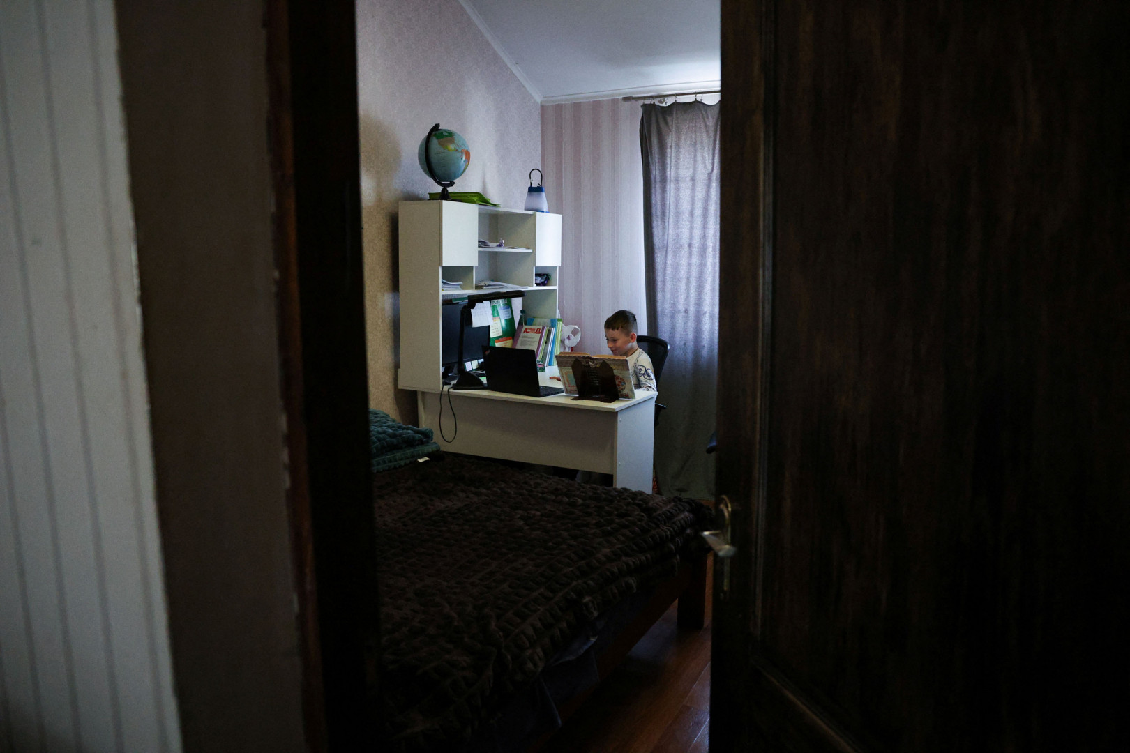A nyolcéves Andrij Tupkalenko távoktatásban tanul a szobájában. Sem ő, sem pedig az öccse sohasem vett részt hagyományos oktatásban – Fotó: Violeta Santos Moura / Reuters
