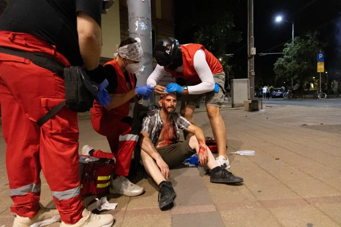 Betört fejű férfit látnak el augusztus 15-én Belgrádban, miután összecsaptak a tüntetők a rohamrendőrökkel – Fotó: Djordje Kojadinovic