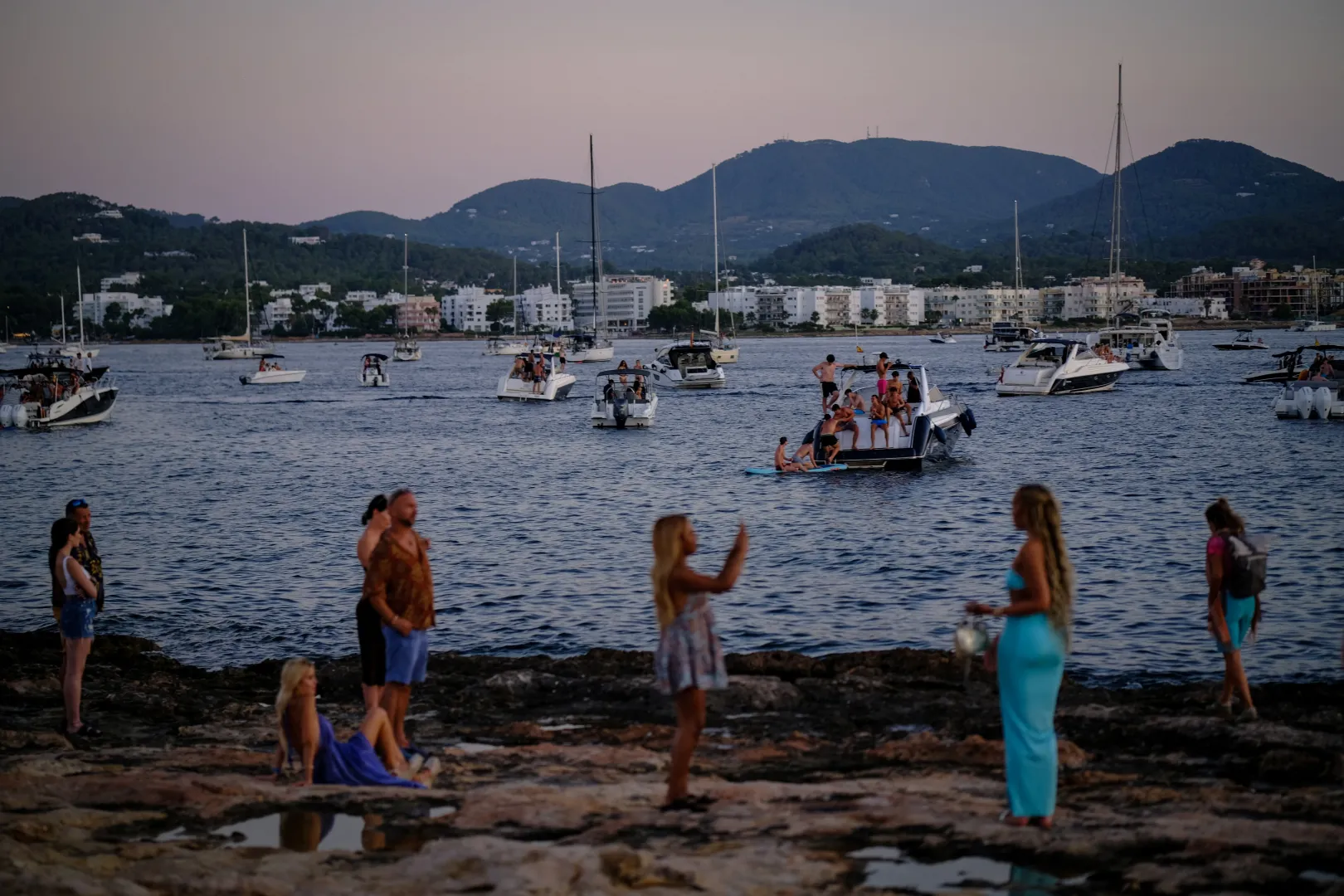 Turisták a parton és hajókon várják a naplementét Sant Antoni de Portmanyban – Fotó: Nacho Doce / Reuters