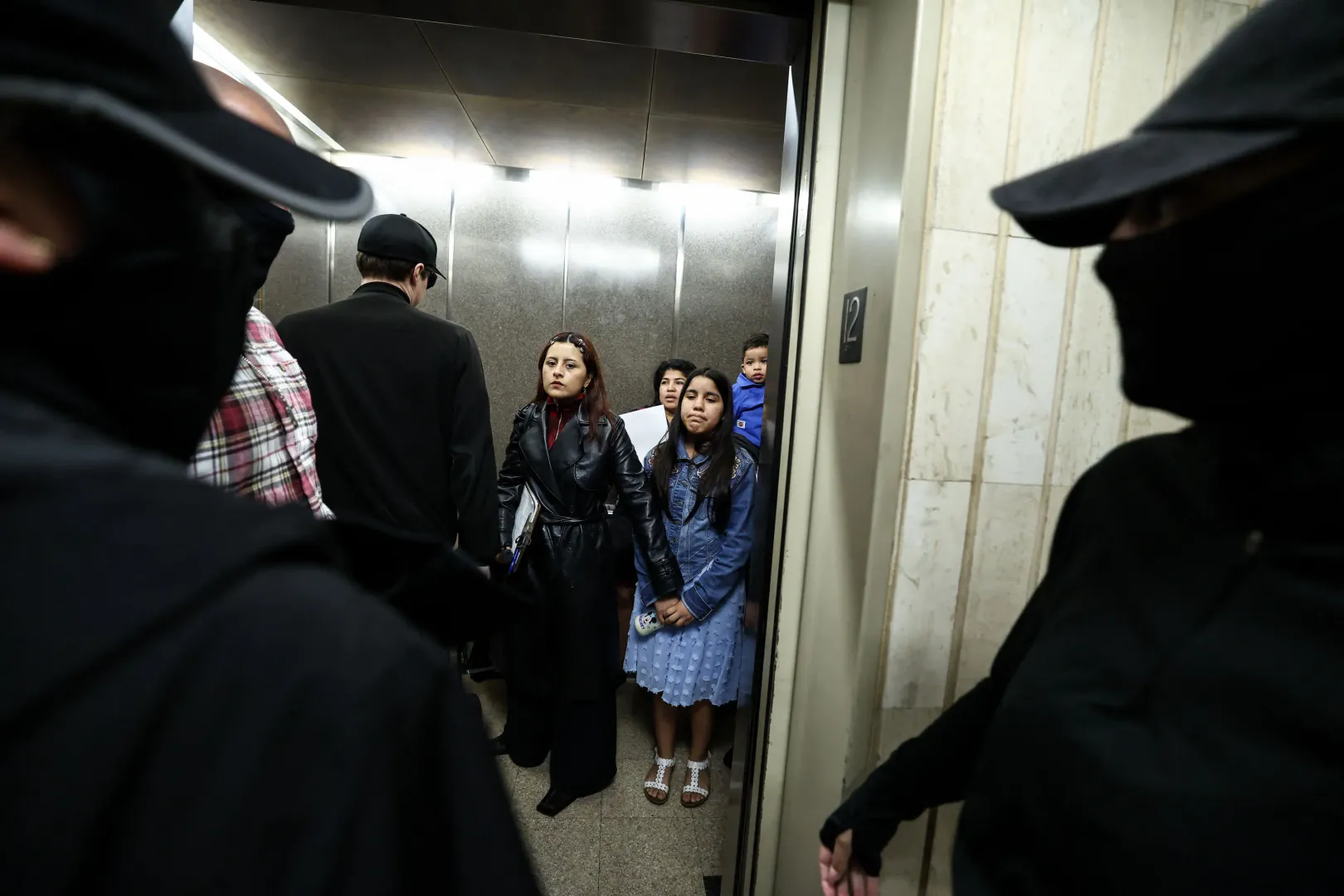 Maszkos ügynökök állnak a liftajtóban, hogy a New York-i bevándorlási bíróságról távozó családok papírjait ellenőrizzék – Fotó: Charly Triballeau / AFP