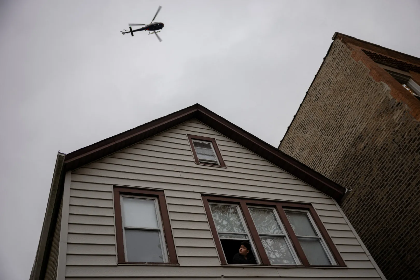 Egy gyerek figyeli a szövetségi hatóságok 2025. november 8-án végrehajtott chicagói akcióját biztosító helikoptert – Fotó: Carlos Barria / Reuters
