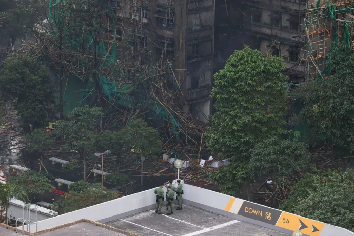 A lángoló bambuszállványzat borítja a Wang Fuk Court lakókomplexum egyik épületén, és az állványzat maradványai az oltást követően – Fotó: Tyrone Siu / Reuters