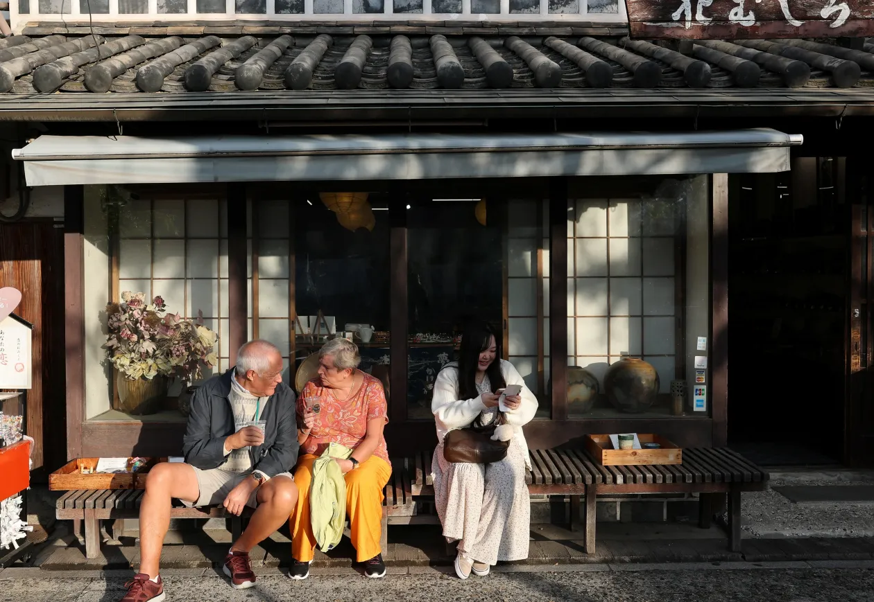 A 32 éves nő omikudzsit, azaz egy hagyományos japán jóslatot tartalmazó cetlit olvas Kurakisiben. Jobbra a Klausszal folytatott üzenetváltások láthatóak – Fotó: Kim Kyung-Hoon / Reuters