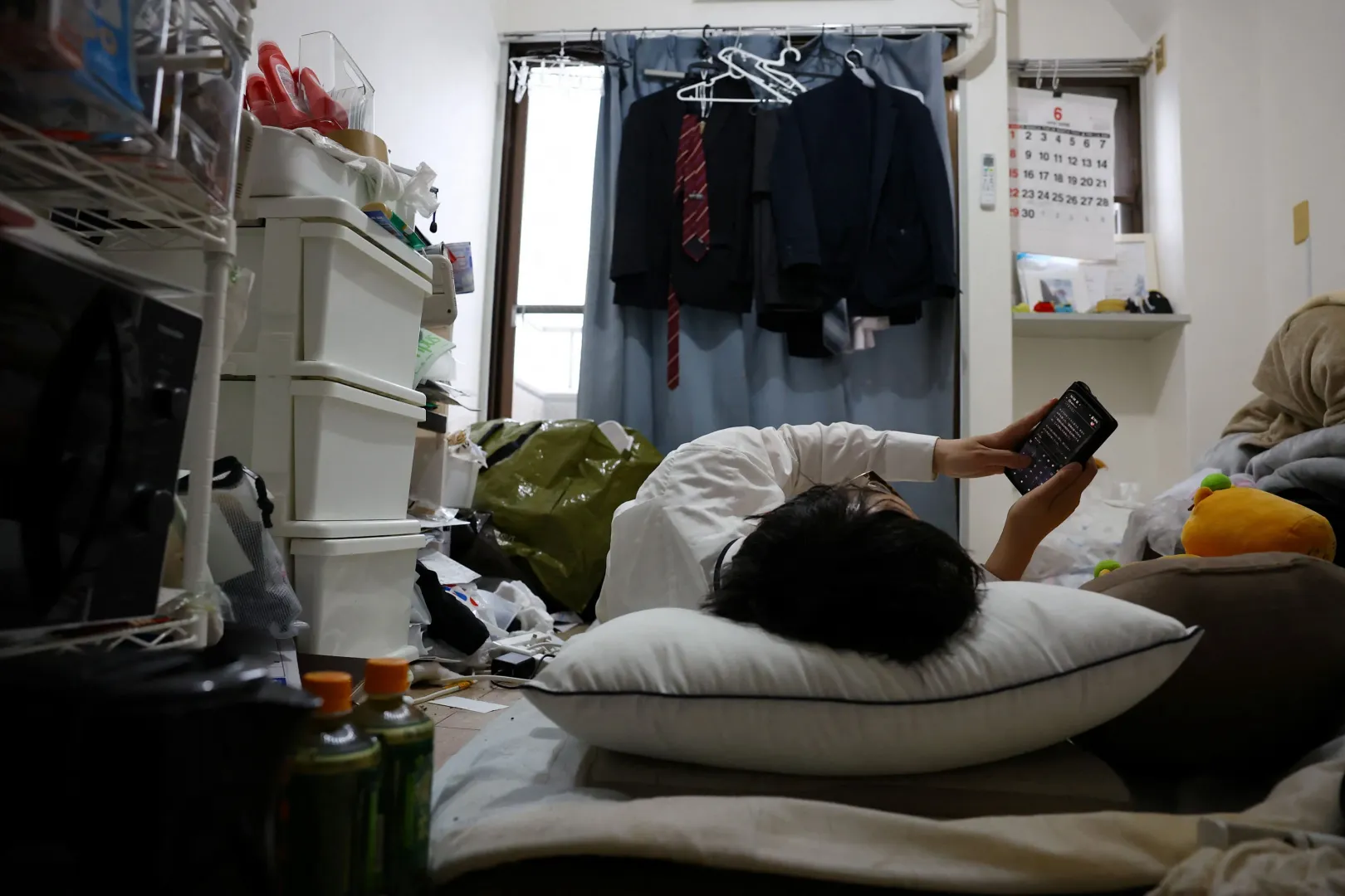 Egy neve elhallgatását kérő japán férfi a tokiói egyszobás lakása padlóján fekve csetel a virtuális barátnőjével – Fotó: Kim Kyung-Hoon / Reuters