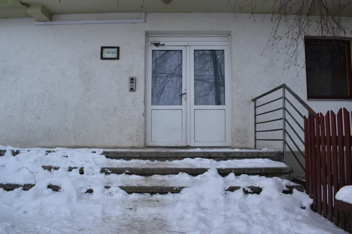 A szociális lakás B lépcsőházának bejárata és Hanzi Klára lépcsőházfelelős – Fotó: Tőkés Hunor / Transtelex