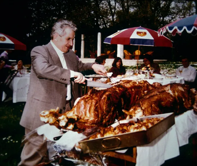 Nicolae Ceaușescu egy családi albumból származó, dátum nélküli felvételen sült malacot szeletel. Miközben az ország lakossága súlyos hiányt és nélkülözést élt meg, a pártvezetés kiváltságos életmódot folytatott – Fotó: Patrick Robert – Corbis / Getty Images