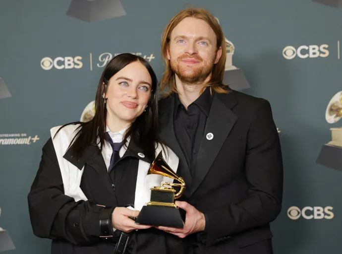 Billie Eilish és Finneas az Év dala díjjal pózolnak a Wildflower című dalért. Mindketten ICE Out feliratú kitűzőt viselnek, amellyel az Egyesült Államok bevándorlási hatóságával (ICE) szembeni tiltakozásuknak adtak hangot – Fotó: Mike Blake / Reuters