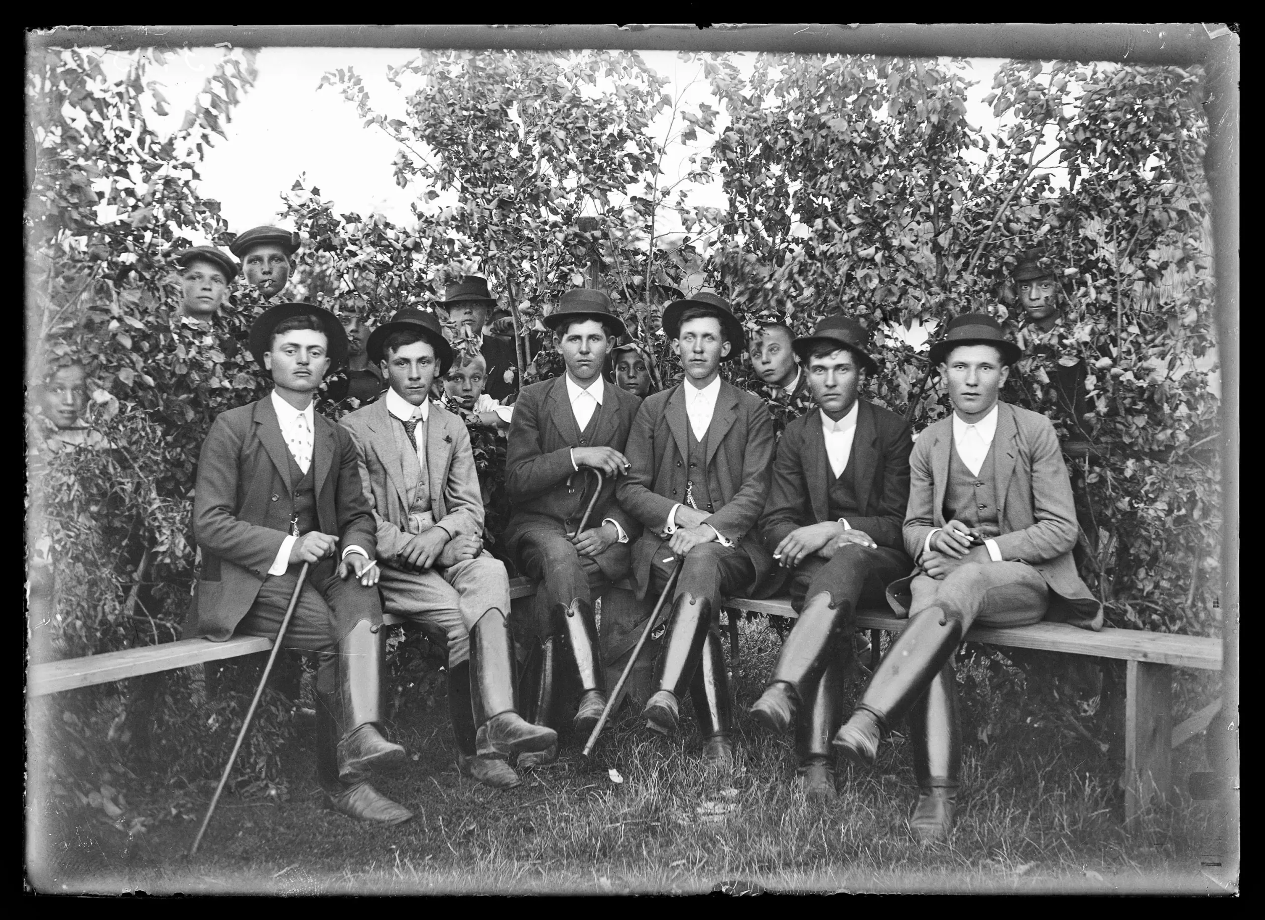 Legények, a bokrok mögött kukucskáló fiúk. Jászárokszállás, 1910-es évek – Fotó: Néprajzi Múzeum Fényképtára / Beck Jenő felvétele