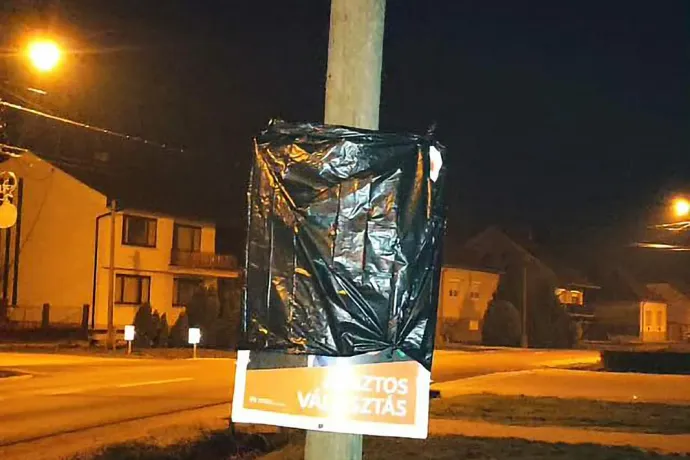 Mécses a babóti utcában a Gyopáros-plakát alatt / A korábban letakart plakátok egyike – Fotó: Cséfalvay Attila / Telex és Nyikos Gábor / Facebook