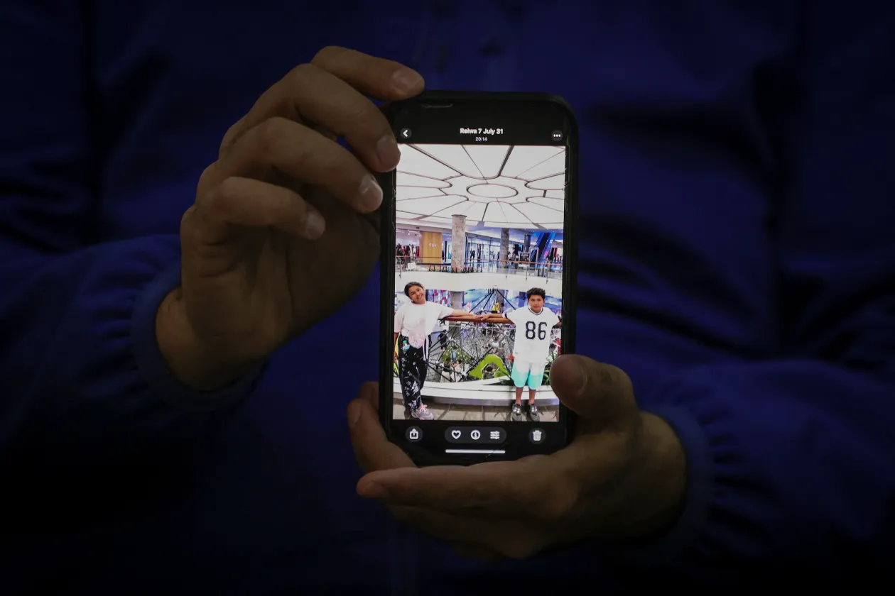 Hamid Sirmohammadzadeht a felesége várta a határnál. Jobbra a gyerekei képét mutatja – Fotó: Dilara Senkaya / Reuters