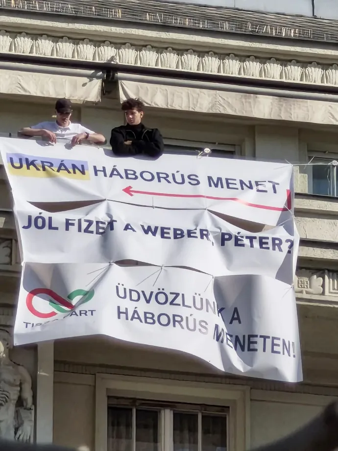 Two young men hold anti-Tisza banners directed at those gathering for the Tisza Party's National March – Photo: Reader photo / Telex