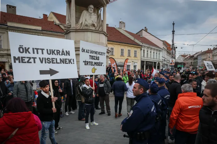 Orbán Viktor országjárásának miskolci állomásán fiatal férfiak az ellentüntetőknek szánt táblákat emelnek magasba 2026. március 21-én – Fotó: Huszti István / Telex