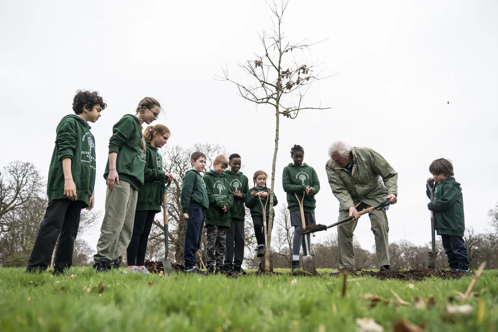 David Attenborough fát ültet II. Erzsébet királynő tiszteletére a londoni Richmond Parkban található The Queen's Green Canopyban iskolás gyerekekkel 2023 márciusában – Fotó: Aaron Chown / PA Images / Getty Images