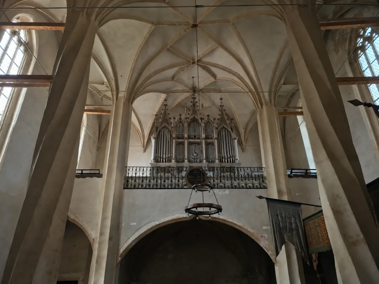 Külső kép: rések a templomfalon, ahonnan lőni is lehetett akár az ellenségre. Templombelső: a különlegesnek számító csavart oszlopok, amilyent csak itt, Szászmuzsnán láttunk – Fotó: a szerző archívuma