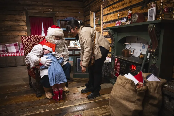 Egy kislányt és édesanyját fogadja a Mikulás a finn Lappföldön, Rovaniemi közelében található irodájában, 2024. november 16-án – Fotó: Jonathan Nackstrand / AFP