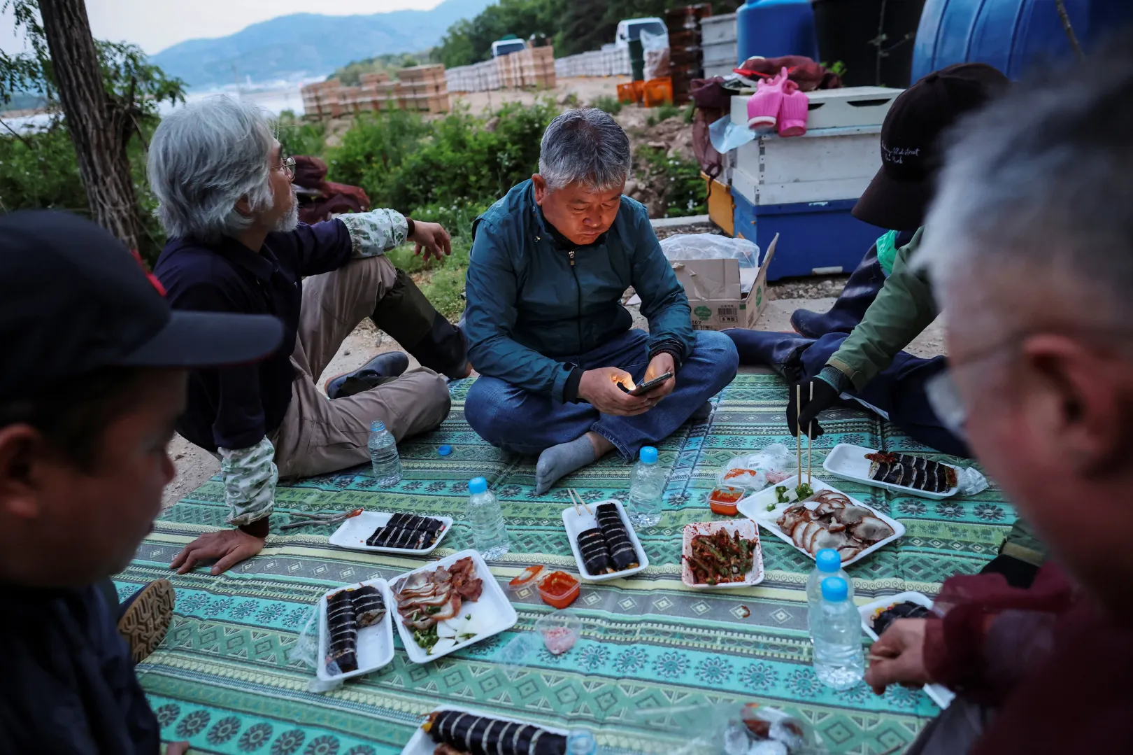 Park Kjongdzse a munkásaival együtt vacsorázik, mielőtt áttelepítik a kaptáraikat egy másik méhlegelőhöz – Fotó: Kim Hong-Ji / Reuters
