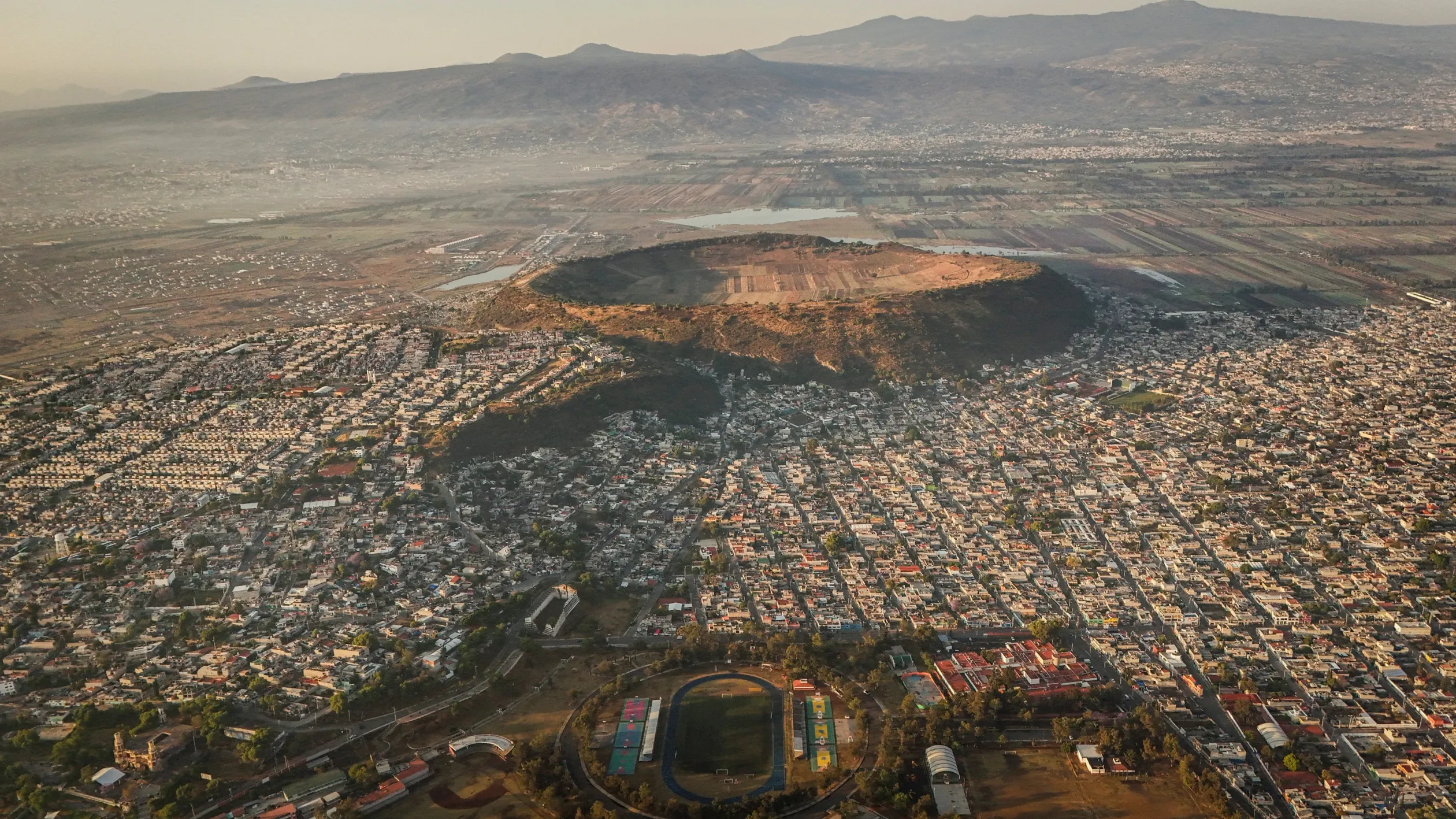 A Luis Donaldo Colosio sportcentrum futballpályája Mexikóvárosban. Háttérben a Xico vulkán krátere, amelyet a helyiek a „világ köldökének” neveznek, 2026. április 8-án– Fotó: Raquel Cunha / Reuters
