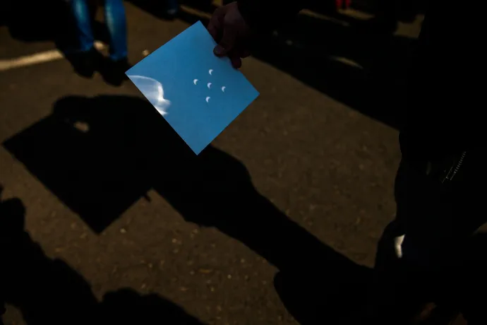 Egy érdeklődő a napfogyatkozás képét vetíti ki egy papírlapra 2015. március 20-án – Fotó: Kurucz Árpád / Anadolu / AFP