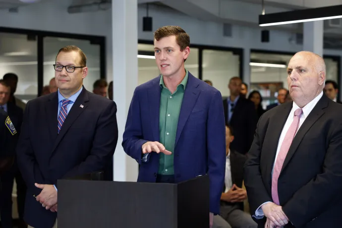 Középen Garrett Langley, a Flock Safety vezérigazgatója és társalapítója beszél a megfigyeléstechnológiai vállalat új bostoni irodájának megnyitóján, mellette balra David Biele massachusettsi állami képviselő és jobbra Ed Flynn bostoni városi tanácsos 2025. július 22-én – Fotó: Danielle Parhizkaran / The Boston Globe / Getty Images