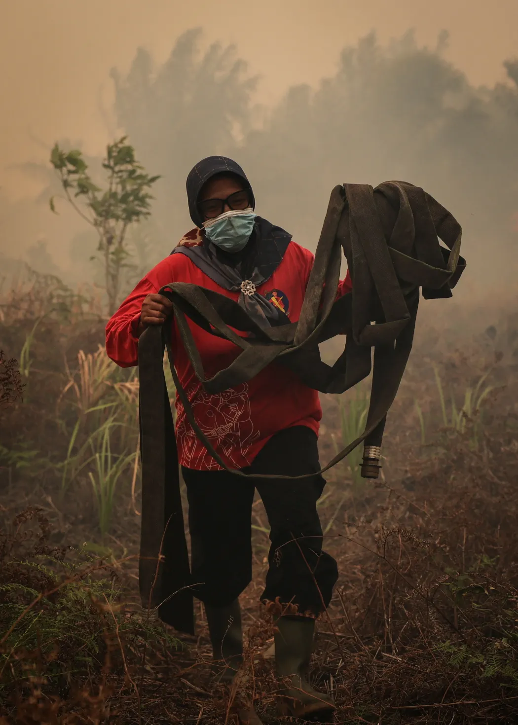A 46 éves Hasimah tűzoltótömlőket készít elő a Sungai Putriban – Fotó: Willy Kurniawan / Reuters